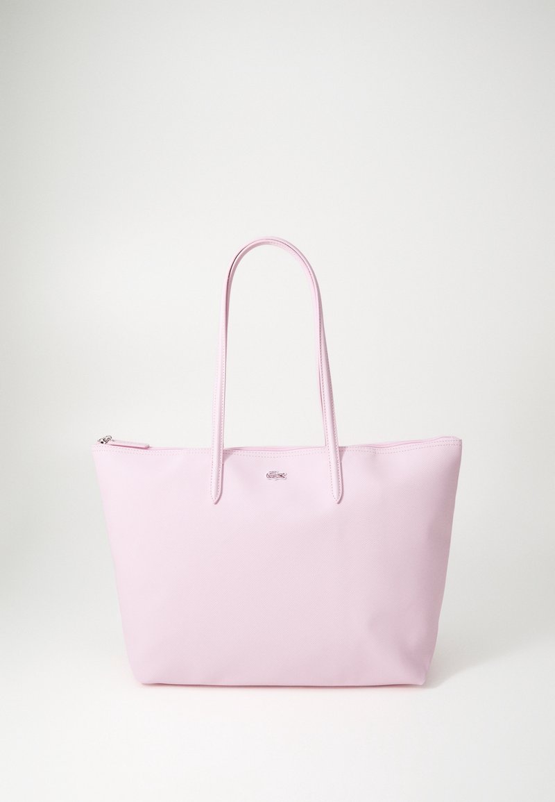 Różowa torba na ramię o gładkiej fakturze, z dwiema długimi rączkami i zapięciem na zamek. Charakteryzuje się minimalistycznym wzornictwem oraz niewielkim logo marki umieszczonym na przedniej części.