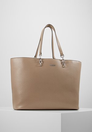 Beżowa torba typu tote ze skóry z dwoma cienkimi uchwytami przymocowanymi srebrnymi łańcuszkami, tłoczonym logo "HUGO" na przodzie, prezentowana na białej powierzchni.