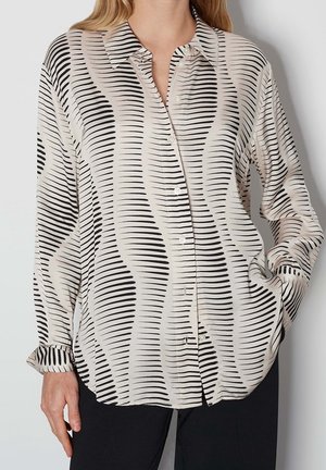 Crèmekleurige blouse met knopen, zwarte golvende strepen, lange mouwen en omgeslagen manchetten. Gemaakt van gladde stof, met een kraag en een losse pasvorm.