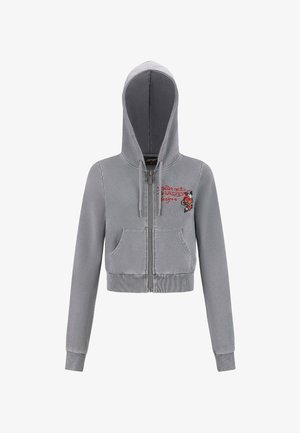 Sudadera gris recortada con cremallera, bolsillos frontales, cordones y el texto "Diseños Ed Hardy" en rojo con un gráfico de rosa en el pecho.