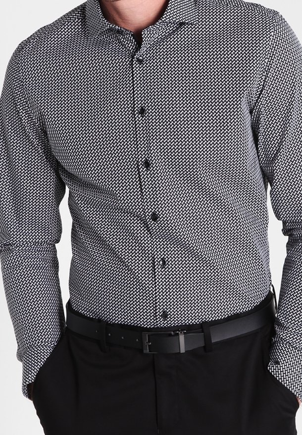 Musta-valkoinen kuvioitu pitkähihainen paita, jossa on napillinen kaulus ja teksturoitu design. Paitaa on yhdistetty mustaan vyöhön ja housuihin.