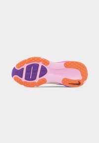 Semelle d'une chaussure de sport avec une base rose, des motifs de crampons orange et violets, et un petit logo swoosh noir sur la zone du talon.
