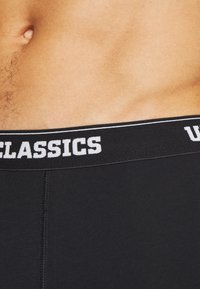 Schwarze Baumwoll-Boxershorts mit einem weichen elastischen Bund, der "CLASSICS" in weißen Buchstaben zeigt. Sie verfügen über eine glatte Textur und ein gut sitzendes Design.