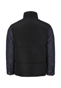 Kurtka pikowana z czarnym pikowanym korpusem i ciemnoniebieskimi rękawami z denimu. Wysoki kołnierz i guziki na mankietach. Przedstawiono widok z tyłu.