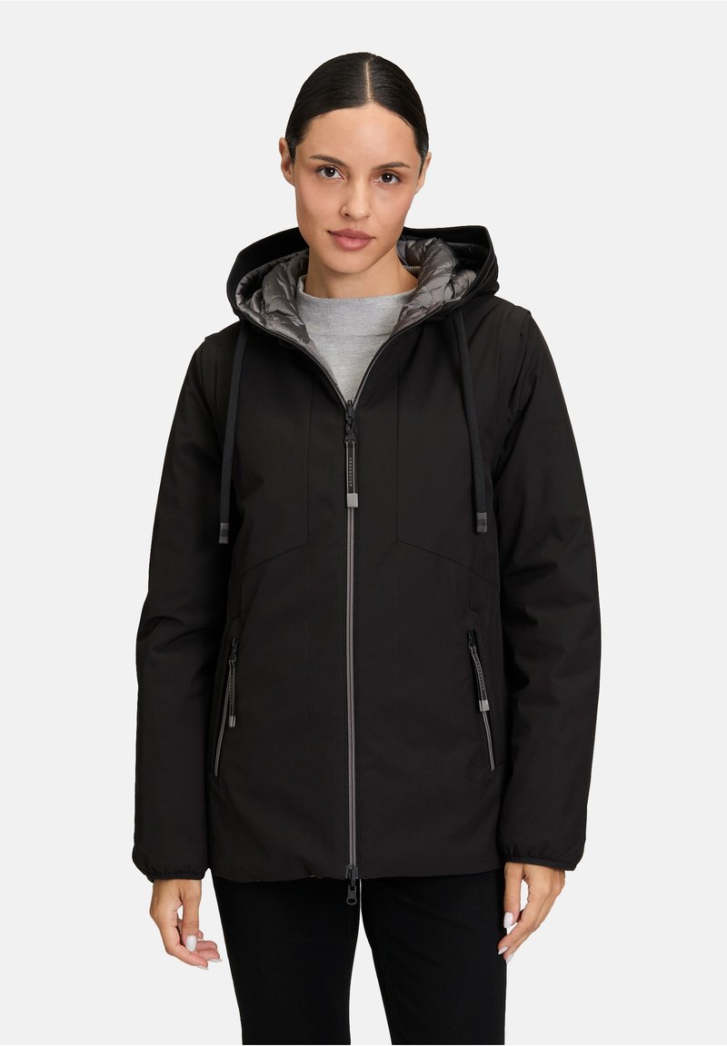 Veste noire isolée avec capuche, dotée d'une doublure matelassée grise, de poches zippées et de cordons de serrage ajustables. Texture lisse et mate.