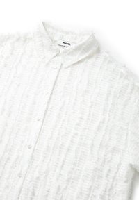 Chemise blanche à boutons, en tissu texturé avec des motifs de fronces verticales, doté d'un col évasé et d'une fermeture à boutons sur le devant.
