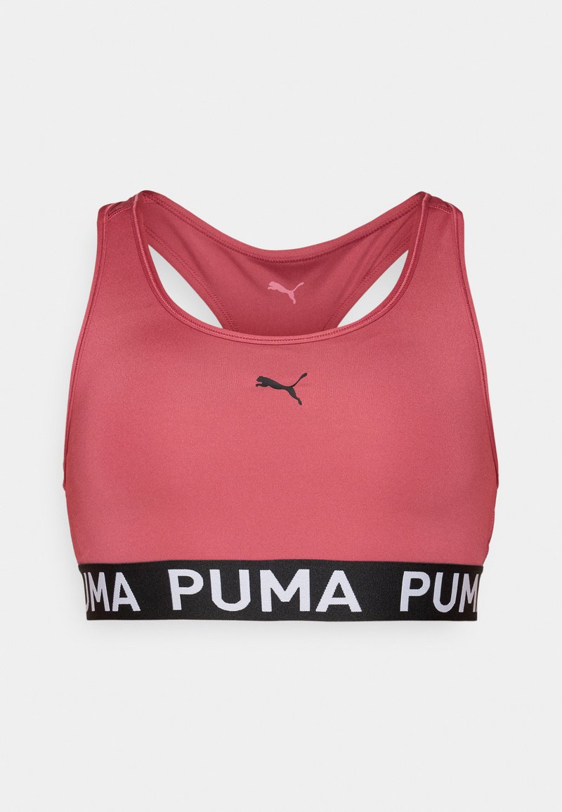Sostén deportivo rosa con diseño de espalda cruzada, hecho de un tejido suave. Presenta una banda negra con "PUMA" en letras blancas y un pequeño logotipo en la parte frontal.
