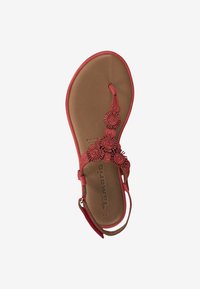 Sandal rojo con adornos florales, suela plana, correa de tobillo ajustable y una plantilla marrón suave, que muestra un diseño de punta abierta.