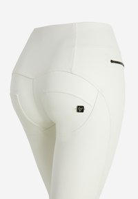 Leggings blancos con una textura suave y elástica. Presentan un bolsillo con cremallera y detalles de costura. Parche con el logo en el bolsillo trasero.