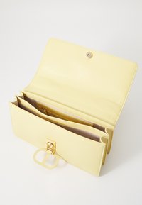 Yellow leather wallet with a snap closure. Features multiple compartments, a smooth texture, and a prominent gold hardware accent.
