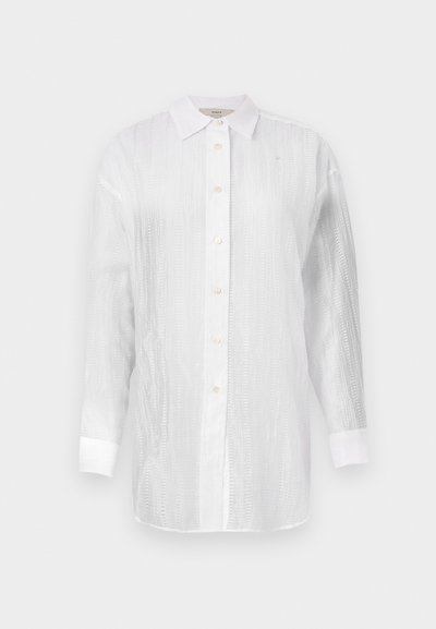 Λευκό πουκάμισο με κουμπιά, φτιαγμένο από υφασμάτινη υφή με διακριτές ρίγες, διαθέτοντας σε ιωνικό γιακά, μακριά μανίκια και στρογγυλές μανσέτες.
