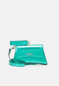 Metallic turquoise handbag with a structured design, gold logo, and adjustable strap. Features a smooth texture and angular shape.