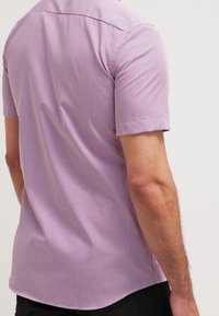 Lyhythihainen paita, jossa on violetti-valkoinen ruutukuvio. Valmistettu kevyestä kankaasta, jossa on sileä pinta ja kaareva helma.