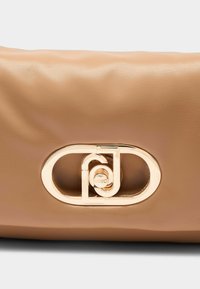 Bolso de piel beige con una textura suave, que presenta un destacado detalle de hardware ovalado en tono dorado, grabado con "LIU JO."