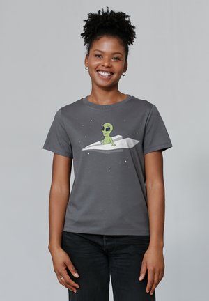 Gray short-sleeve t-shirt featuring a green cartoon alien on a white paper airplane against a starry background. Soft cotton fabric.