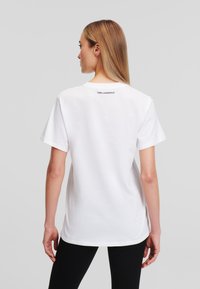 Witte katoenen T-shirt, korte mouwen, ronde hals, met het logo "KARL LAGERFELD" gedrukt op de bovenrug. Achteraanzicht toont een comfortabele pasvorm.