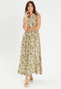 Floral patterned maxi dress with a collar, featuring greens and beige tones, and a cinched waist. Worn with gold platform sandals.