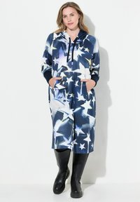 Hooded jumpsuit i marinblått med stjärntryck, med fickor och en avslappnad passform. Tillverkad av mjukt tyg, med lång ärm och ribbade manschetter.