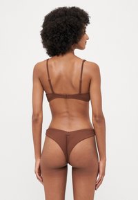 Brown ribbed bikini set with adjustable straps and a hook closure on the bra. The bottoms feature a high cut and a seamless waistband.