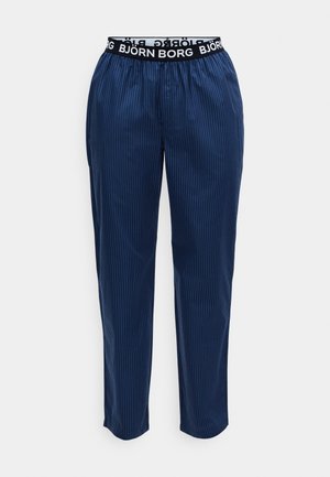 Calças de pijama azuis marinho com riscas verticais, cintura elástica com logótipo e design de perna afunilada. Textura de tecido suave.