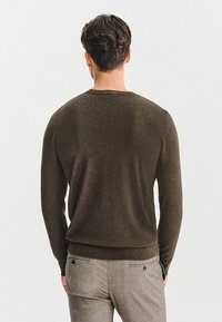 Brązowy sweter z dzianiny z okrągłym dekoltem, żeberkowym wykończeniem i długimi rękawami. Gładka faktura na jednolitym tle. Casualowy design.