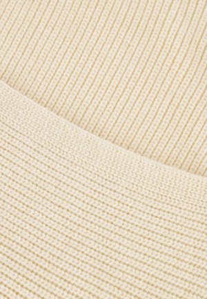 Primer plano de una tela de punto ribeteado beige con un borde doblado que muestra dos patrones y texturas de tejido diferentes.