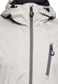 Jasna szara wodoodporna kurtka z wzorem w kratę, zamkiem błyskawicznym z przodu, kieszenią na piersi i regulowanym kapturem z czarnymi stoperami.