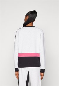 Sudadera gris con un borde a rayas rosas y negras, mangas raglán y puños acanalados. Tejido suave con un diseño casual.