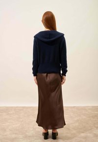 Laivaston huppari, joka on valmistettu pehmeästä kankaasta, yhdistettynä tummanruskeaan satiinihameeseen. Asu on rentoa tyyliä ja siinä on sileä pinta.