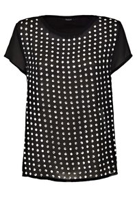 Top negro de manga corta con tejido transparente, adornado con tachuelas circulares plateadas dispuestas en un patrón de cuadrícula. Cuello redondo clásico.