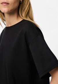 Zwarte katoenen t-shirt met een ronde hals en korte mouwen, met een zachte textuur en een relaxte pasvorm, met een minimalistisch ontwerp.