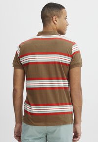 Stribet polo-shirt i brun med røde og turkise striber. Korte ærmer og kravehals med sideslids for komfort.
