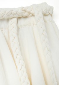 Falda de tela blanca con detalle trenzado en la cintura, textura suave y diseño fluido para un ajuste cómodo.