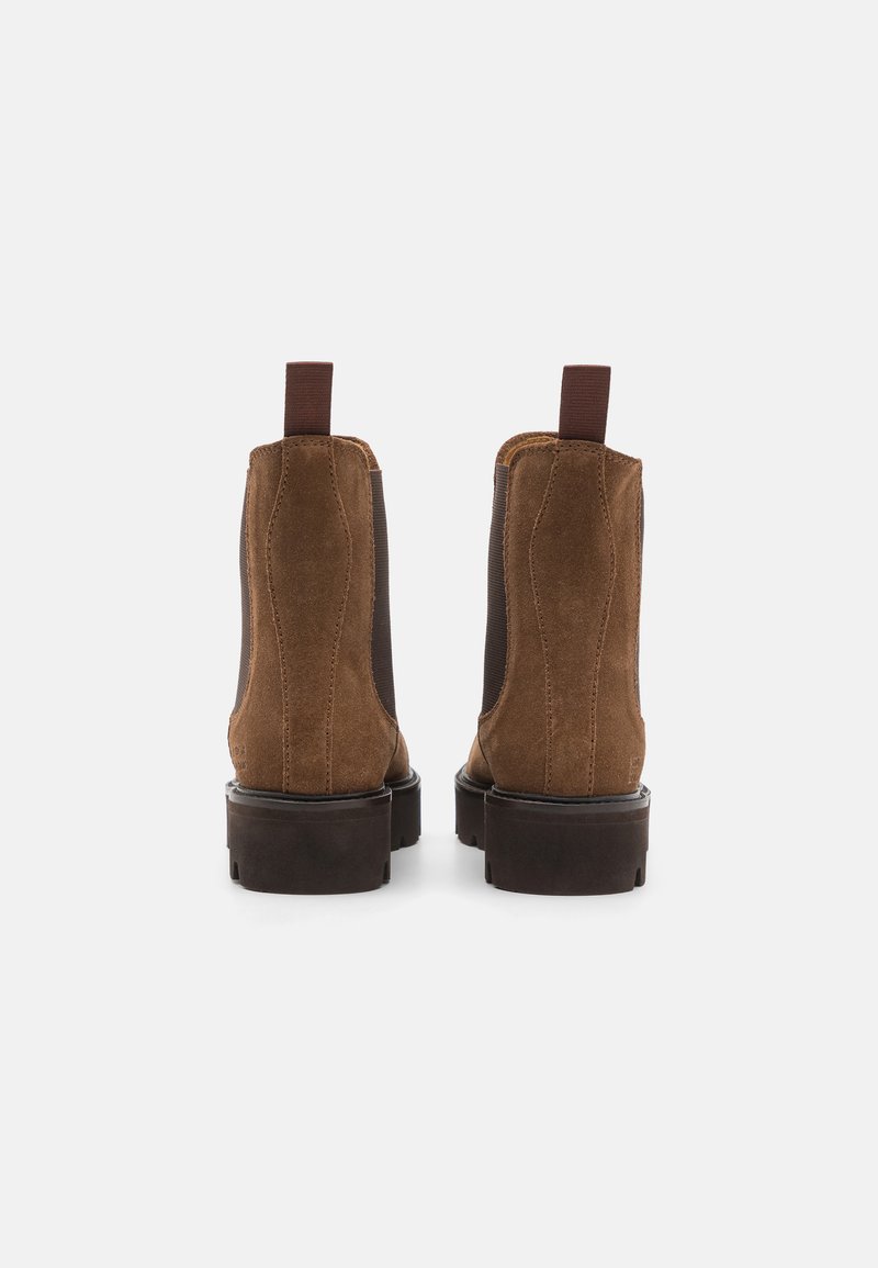 Braune Wildleder-Stiefeletten mit elastischen Seiteneinsätzen, Ziehschlaufen und einer dicken Gummisohle; zeichnen sich durch eine glatte Textur und ein minimalistisches Design aus.