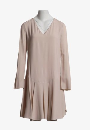 Robe beige à manches longues avec col en V et jupe plissée, exposée sur un buste de mannequin blanc sur fond blanc.