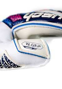 Vit målvaktshandske med blå accenter, texturerat greppområde och ett mönstrat handledsområde. Har en "RE:GRIP"-etikett på handleden.