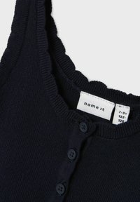 Navy blue knit tank top with a ruffled neckline and four button closures. Features a care label with size range 7-8 years.