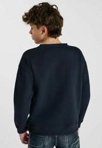 Navyblauwe sweatshirt met een ronde hals en geribbelde boorden; zachte stof, relaxed fit en zichtbare stikdetails op de achterkant.