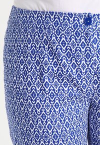 Blue and white patterned fabric featuring a geometric design. Includes a visible blue button at the waist and textured surface.
