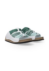 Twee paar moderne sandalen met een mix van groene en witte banden, een met een textuur afgewerkte voetbed en zwarte zolen.