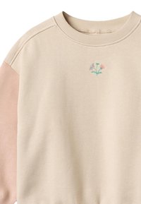 Sweatshirt beige avec manches roses, présentant un petit motif floral brodé en bleu et rose, fabriqué en tissu doux avec col côtelé.