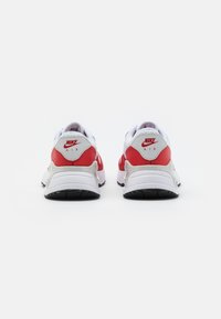 Scarpe Nike Air con una tomaia in mesh bianco, dettagli in pelle rossa e suola in gomma nera. Presentano un retro arrotondato e il logo sul tallone.