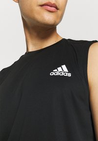 Débardeur de sport noir avec un tissu texturé et le logo Adidas blanc sur la poitrine. Doté d'un col rond et d'un design épuré.