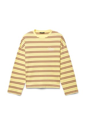 Chemise jaune à manches longues avec des rayures horizontales rouges et un petit texte blanc en haut à gauche, posée à plat sur fond blanc.