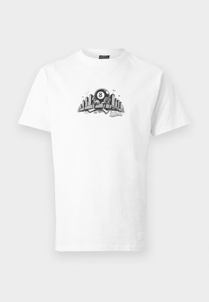 T-shirt blanc avec un graphisme noir et blanc représentant un personnage de boule 8 tenant un paysage urbain avec des bâtiments et des oiseaux au-dessus.