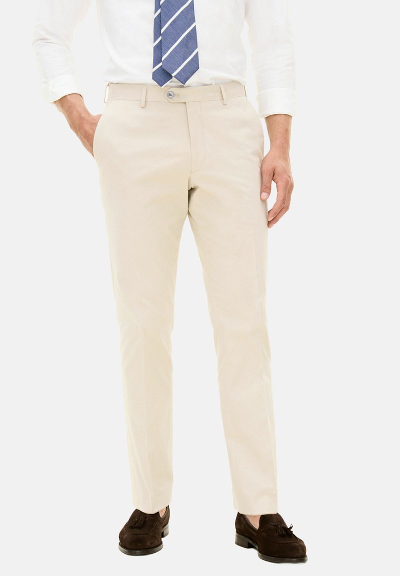 Pantaloni in cotone beige con design a gamba dritta, dotati di tasche frontali, chiusura con bottone e scarpe in pelle scamosciata marroni.