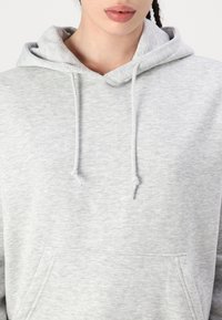Gray cotton hoodie with a front pocket, adjustable drawstrings, and a soft texture. Features a classic hooded design.
