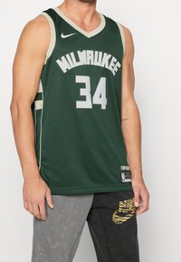 Maglia da basket verde dei Milwaukee Bucks con dettagli bianchi, con il numero 34 e il testo "MILWAUKEE", realizzata in tessuto a rete traspirante.
