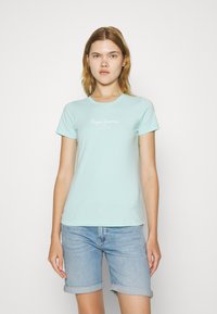 Svijetloplava majica kratkih rukava od pamuka, s bijelim natpisom "Pepe Jeans London" sprijeda. Par zarolane traper šortse.