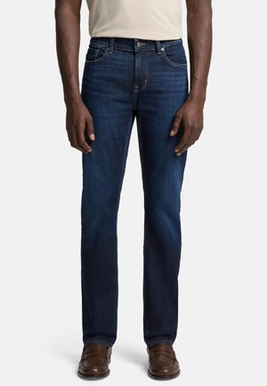 Men's dark blue denim jeans with a straight-leg cut, mid-rise waist, subtle stitching, and five-pocket design. Worn with brown shoes.